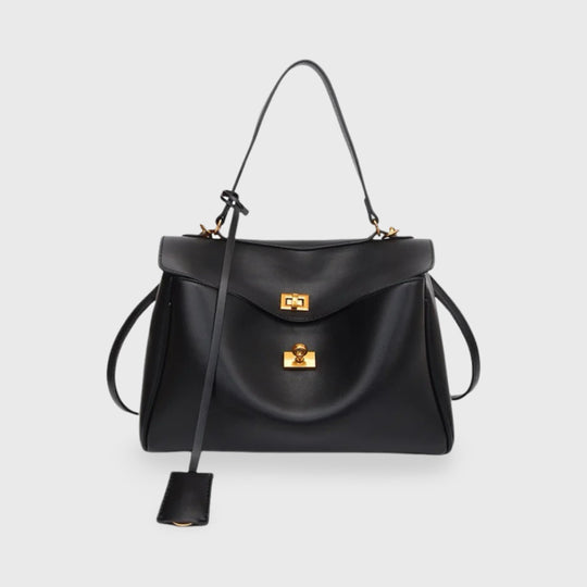 Black structured leather handbag with a gold clasp and long shoulder strap