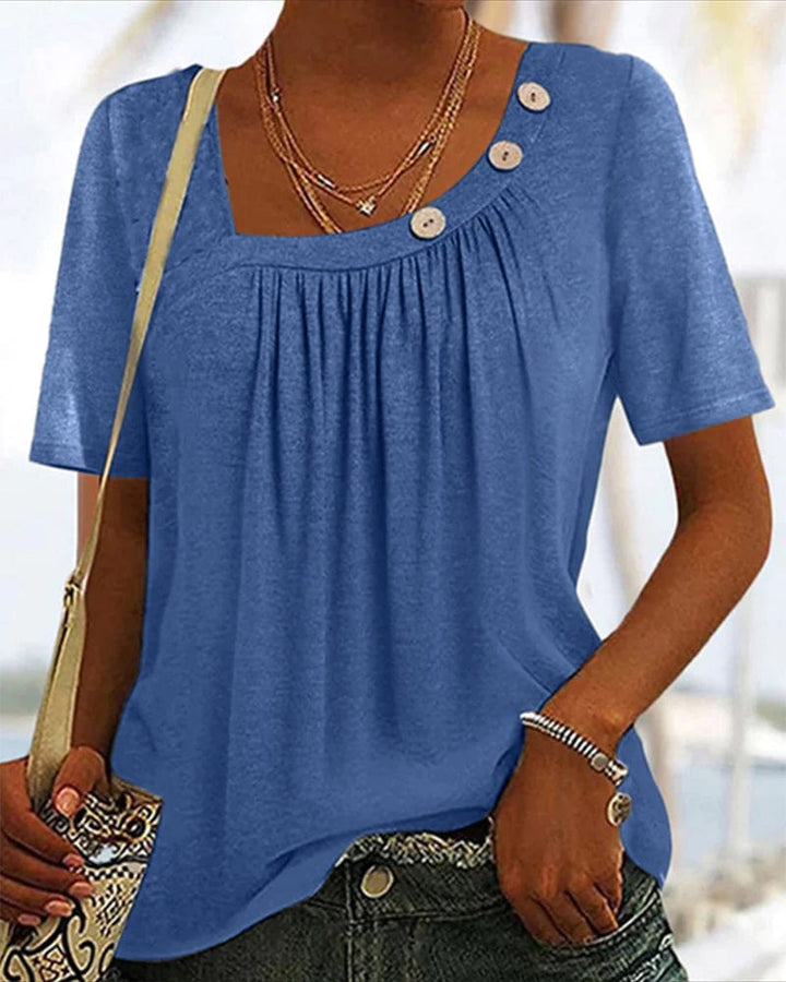 Close up front view of a model wearing a comfortable short sleeve blouse with a square neckline and decorative buttons