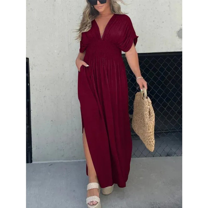 Front view of model wearing a maroon elegant summer maxi dress with side split and pockets, holding a woven bag