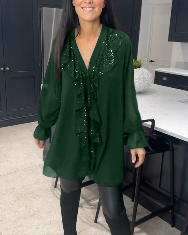 Front view of a woman wearing a green ruffled blouse with sequin detail over black over-the-knee boots