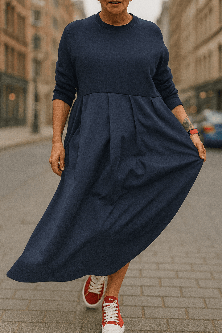Front view, model wearing a navy oversized long sleeve dress with a round neck and pleated skirt detail