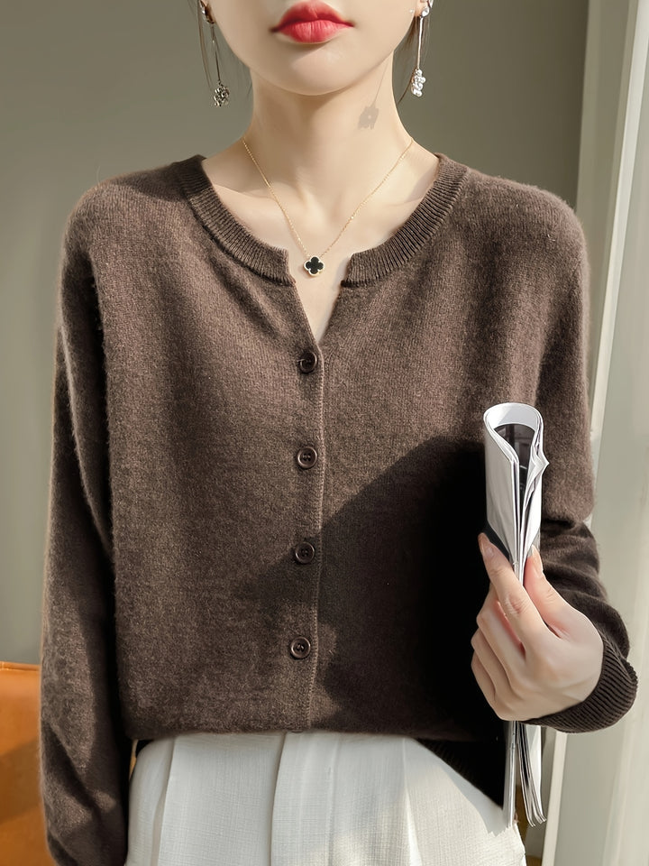 Front view of a model wearing the brown buttoned knit cardigan with a clover necklace and white pants