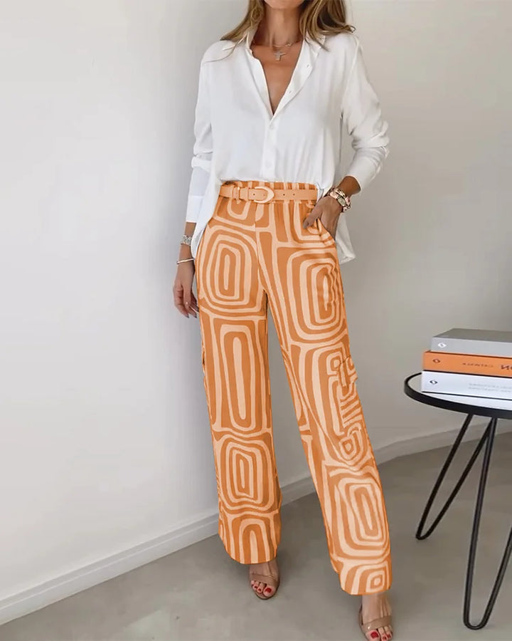 White blouse with orange and beige patterned trousers and a belt