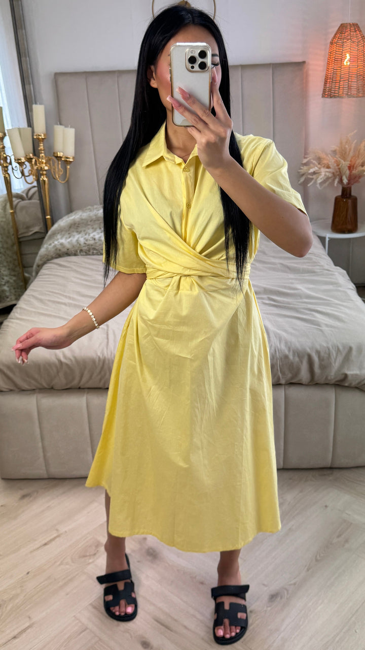 Front view, worn by model, a yellow cross tie belt blouse dress in soft cotton blend with a phone covering her face
