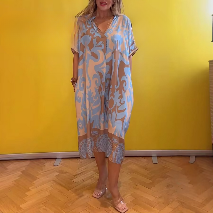 Front view of model wearing a loose elegant floral dress in cotton linen blend with short sleeves and colourful flowers