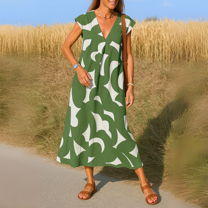 Front view of a woman wearing a green and white patterned flowing V-neck boho dress with brown sandals