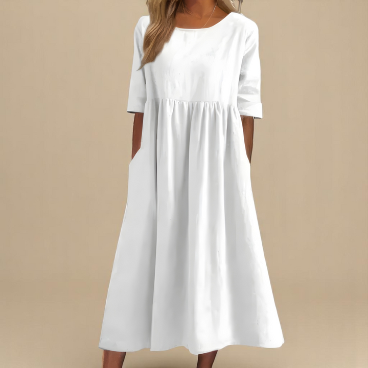 Front view of a model wearing a white soft cotton airy dress with three quarter sleeves and side pockets