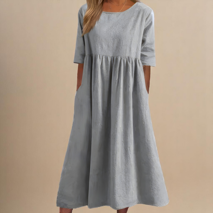 Front view of a model wearing a light grey soft cotton airy dress with three quarter sleeves and side pockets