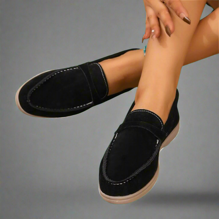 Ellis Elegant Flat Shoes in black suede with white topstitching and light brown soles, worn by model