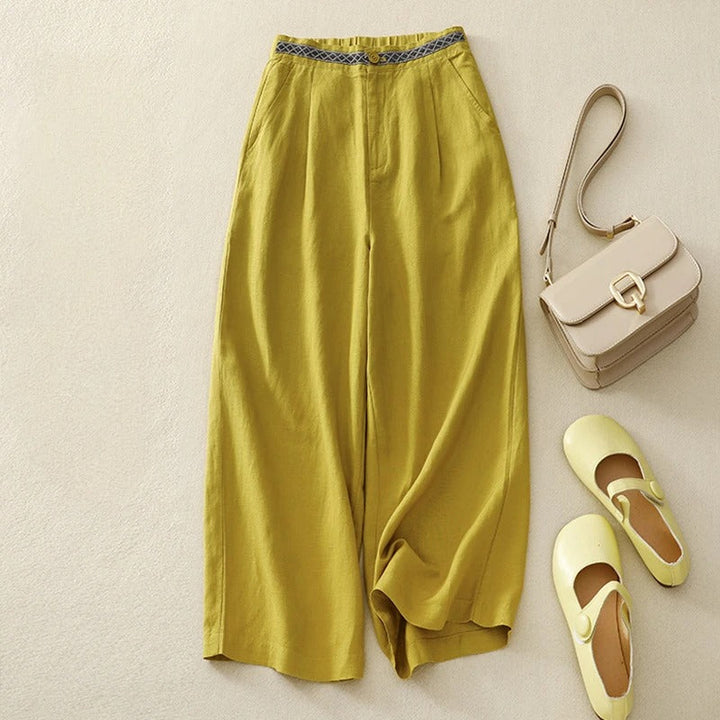Flat lay of yellow linen pants with a patterned waistband, styled with a handbag and shoes