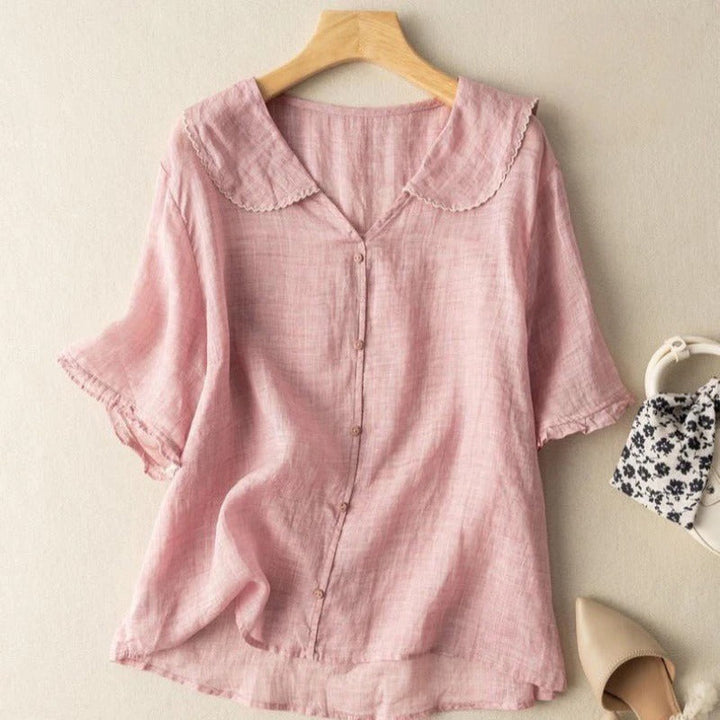 Front view of a pink lightweight linen blouse with a scalloped collar and short sleeves, styled with accessories