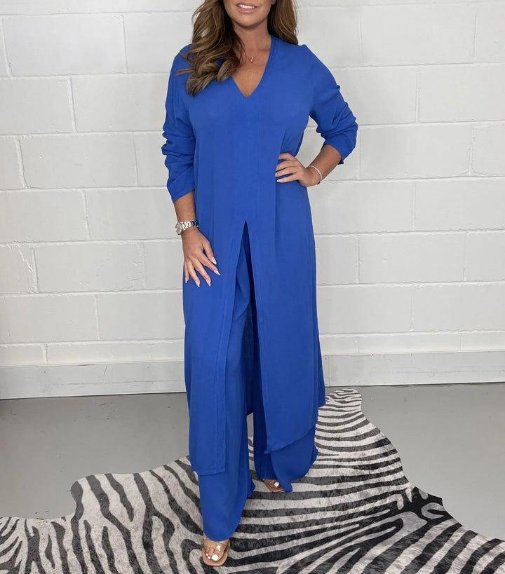 Front view of a model in a royal blue two-piece wide leg jumpsuit set with a long tunic top and v-neck
