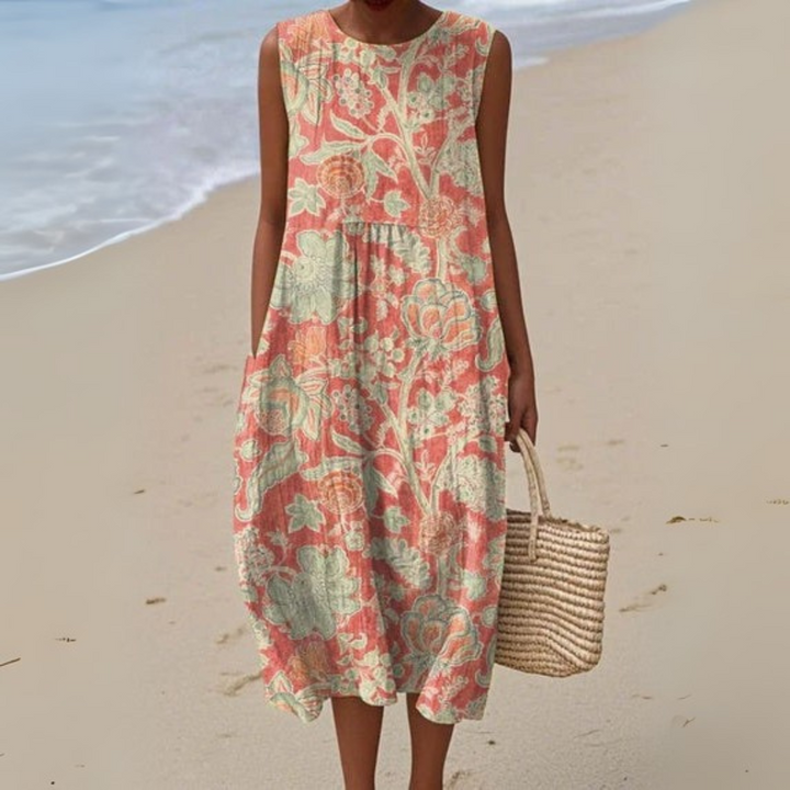 Front view of a model wearing a Vintage Floral Cotton Dress with a straw bag on a sandy beach