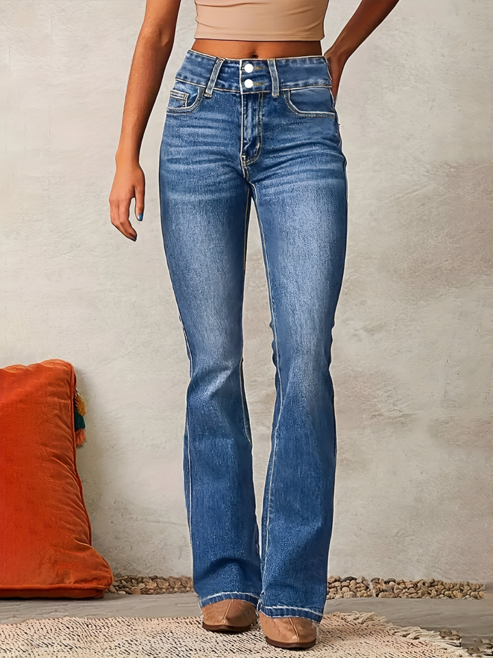 Front view of a model wearing high-waisted flared jeans in vintage blue denim with a beige crop top