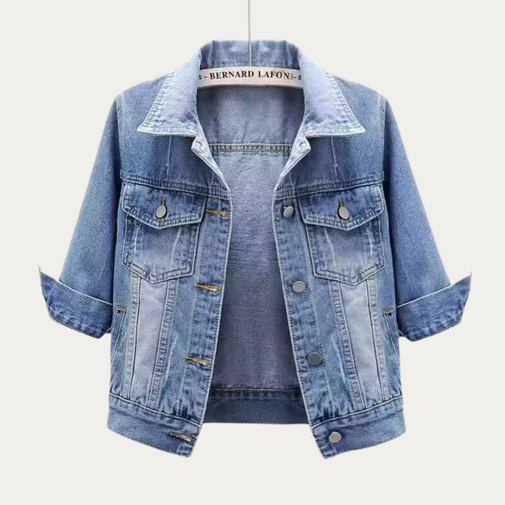 Front view of a light wash denim jacket with rolled up three quarter sleeves, on a hanger