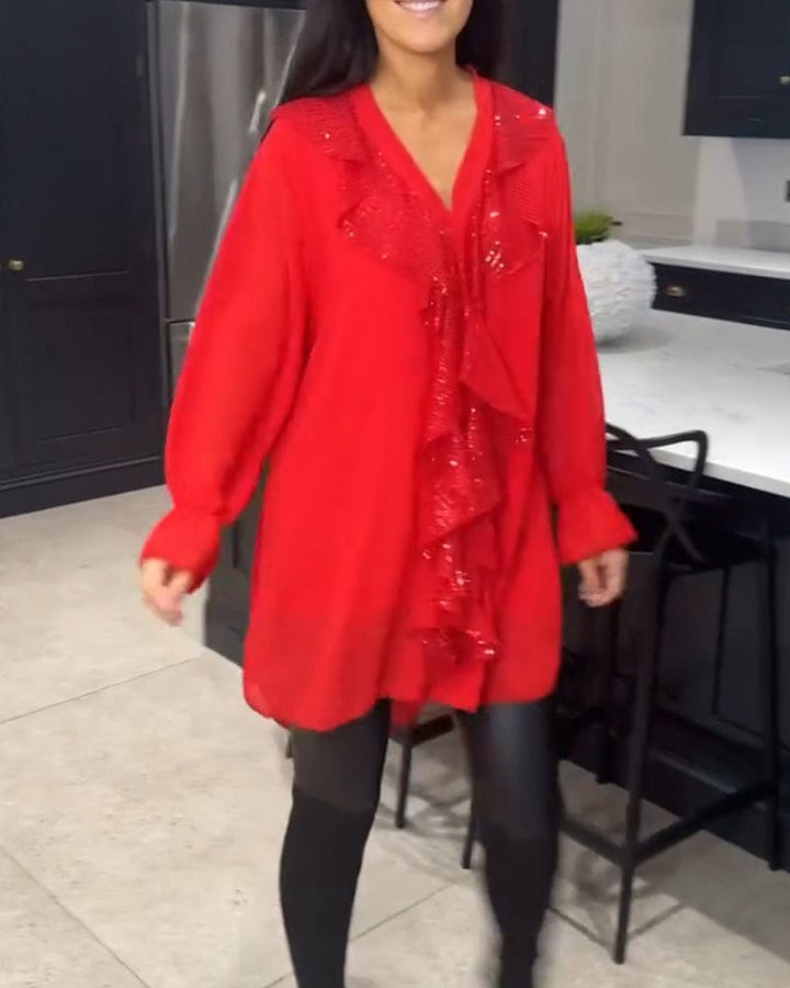 Front view of a woman wearing a red ruffled blouse with sequin detail over black leggings