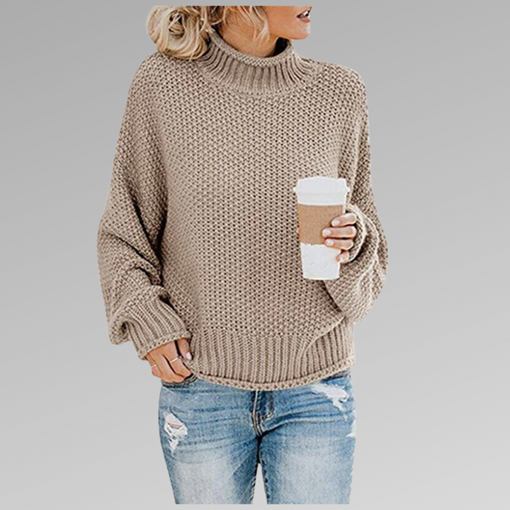 Front view of model wearing the beige Jovana Airy Touch Knit top with ripped jeans and holding a coffee cup