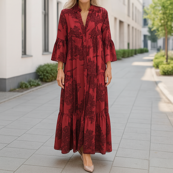 Front view of an elegant floral dress worn by model, a long red cotton blend dress with tiered skirt and bell sleeves
