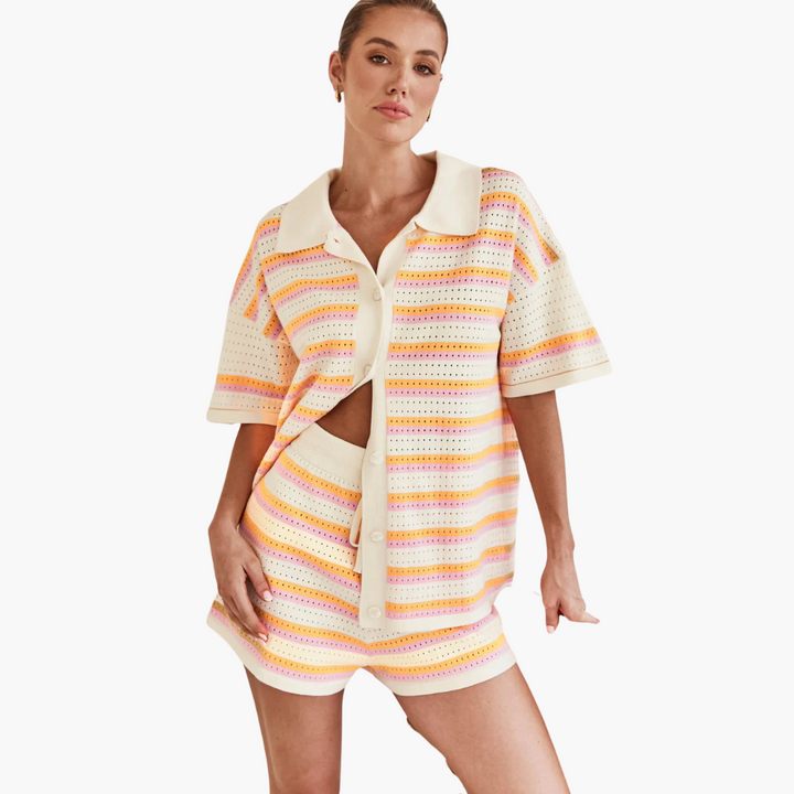 Front view of a model wearing a striped shirt and shorts two-piece set in cream, orange and pink stripes