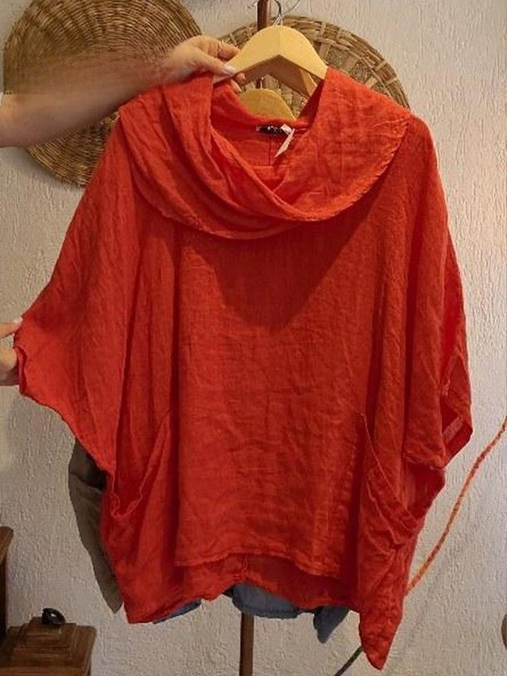 Front view of a red linen pocket top with a draped neck and 3/4 sleeves, held on a wooden hanger