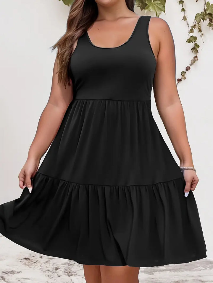 Front view of a plus-size model wearing a sleeveless black tiered dress, hands lifting the hem slightly