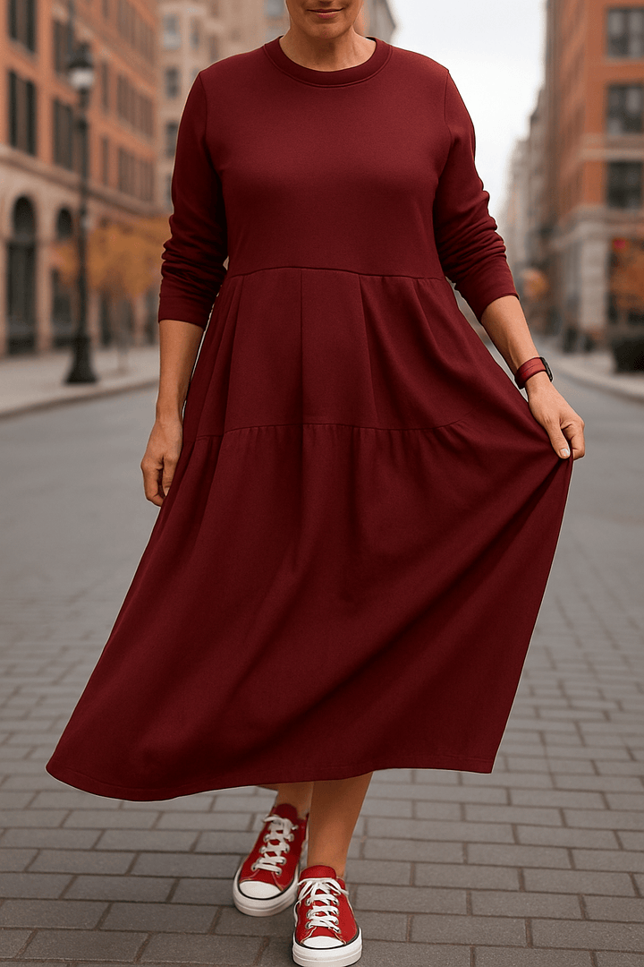 Front view, model wearing a maroon oversized long sleeve dress with a round neck and tiered skirt detail