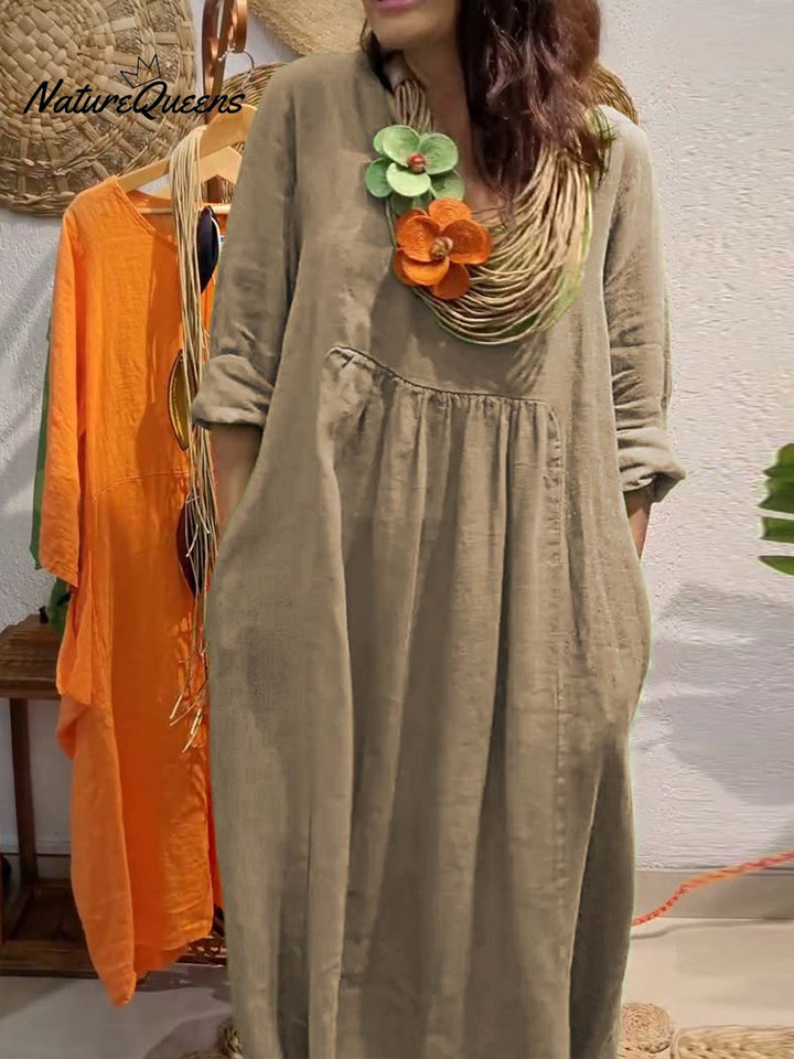Three quarter view, model wearing a long khaki V-neck cotton linen dress with 3/4 sleeves and large pockets