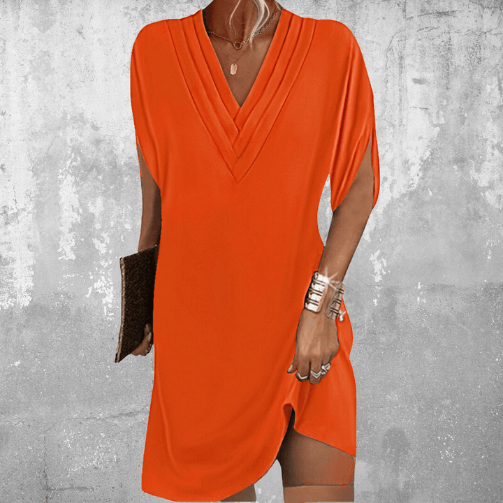Front view of model wearing the Grace elegant tummy-flattering A-line dress in orange with a clutch and jewellery