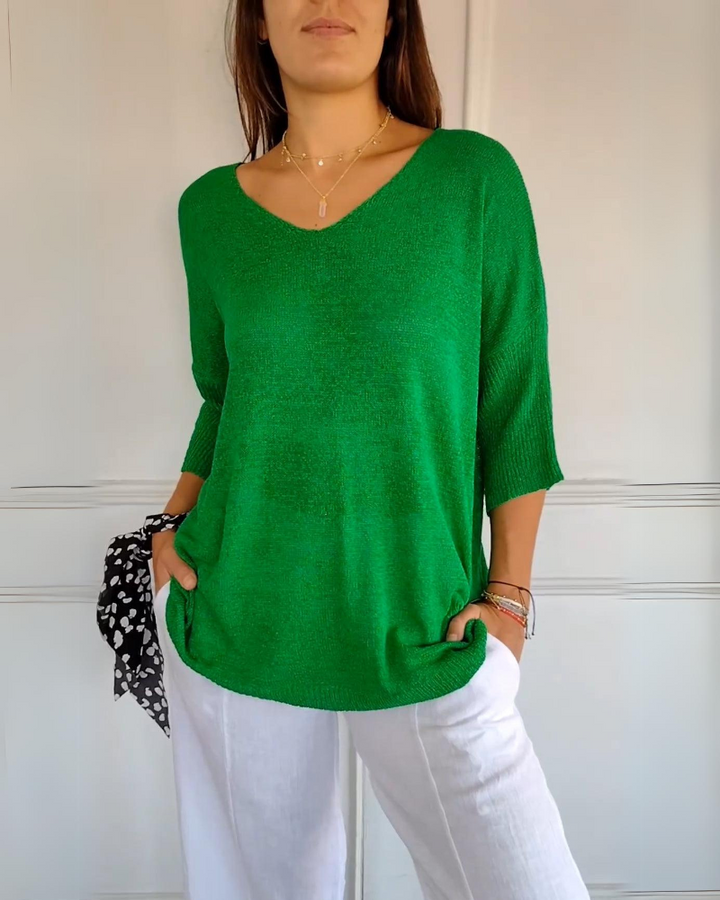 Front view of a model wearing a bright green breathable cotton top with a V neck and white linen pants