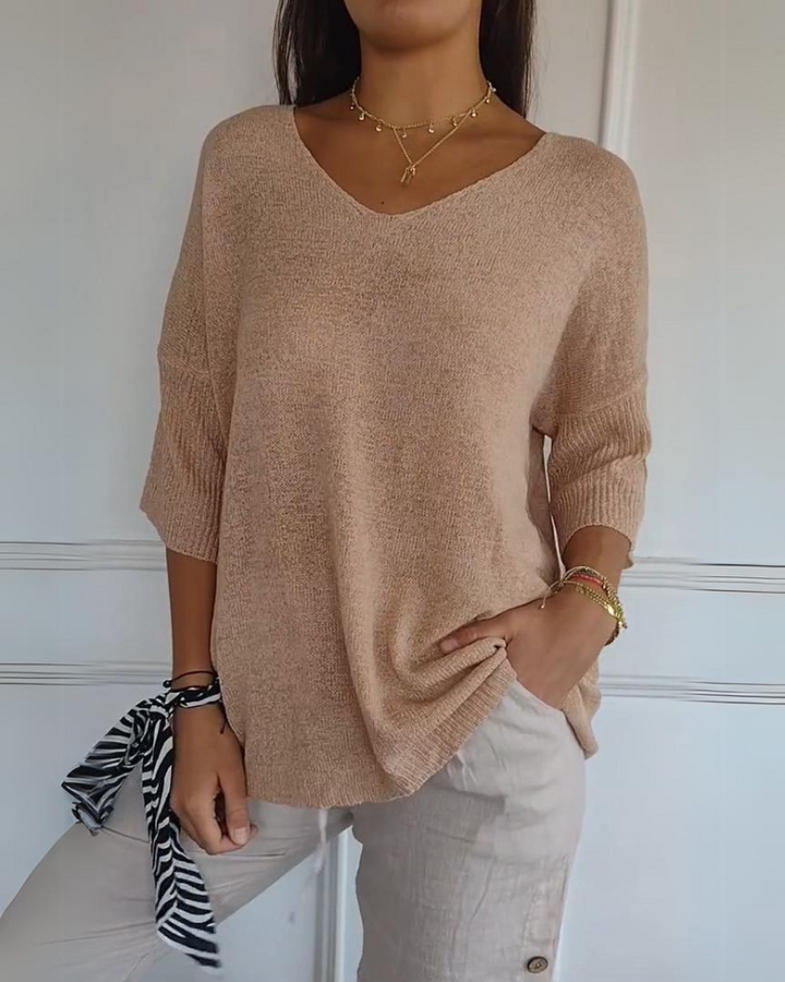 Front view of a model wearing a coral pink breathable cotton top with 3/4 sleeves and light beige linen pants