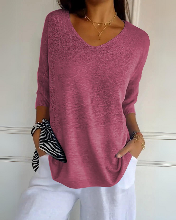 Front view of a model wearing a coral pink breathable cotton top with a V neck and white linen pants