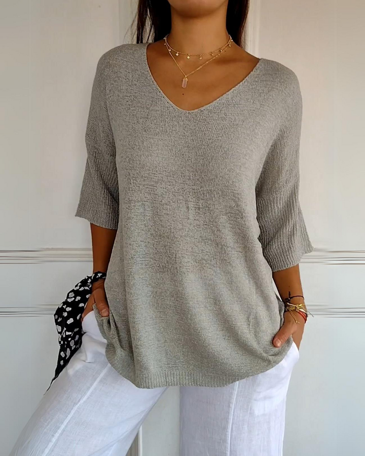 Front view of a model wearing a light grey breathable cotton top with a V neck and white linen pants