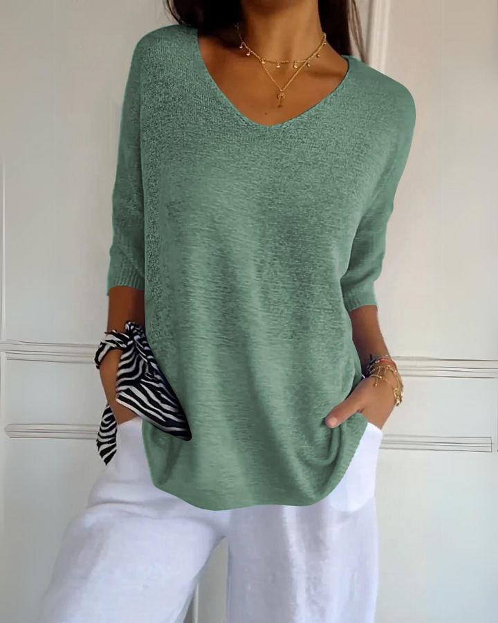 Front view of a model wearing a bright green breathable cotton top with a V neck and white linen pants with pockets