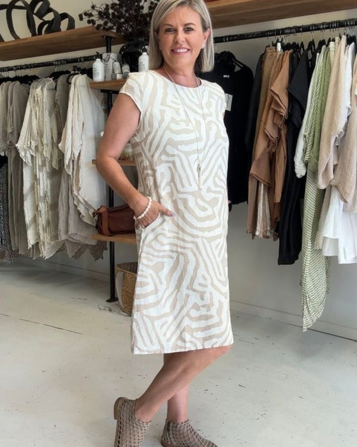 Side view, model wearing a zebra print boho summer midi dress with one hand in pocket, smiling