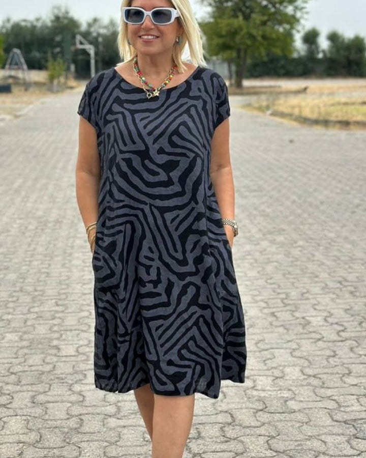 Front view, model wearing a zebra print boho summer midi dress, hands in pockets, smiling, alternate angle