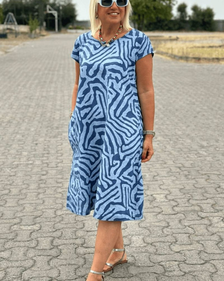 Front view, model wearing a zebra print boho summer midi dress with silver sandals and white sunglasses