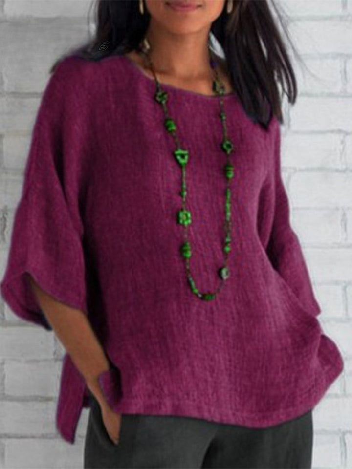 Front view of a model wearing a plum crewneck cotton linen shirt top with a long green beaded necklace