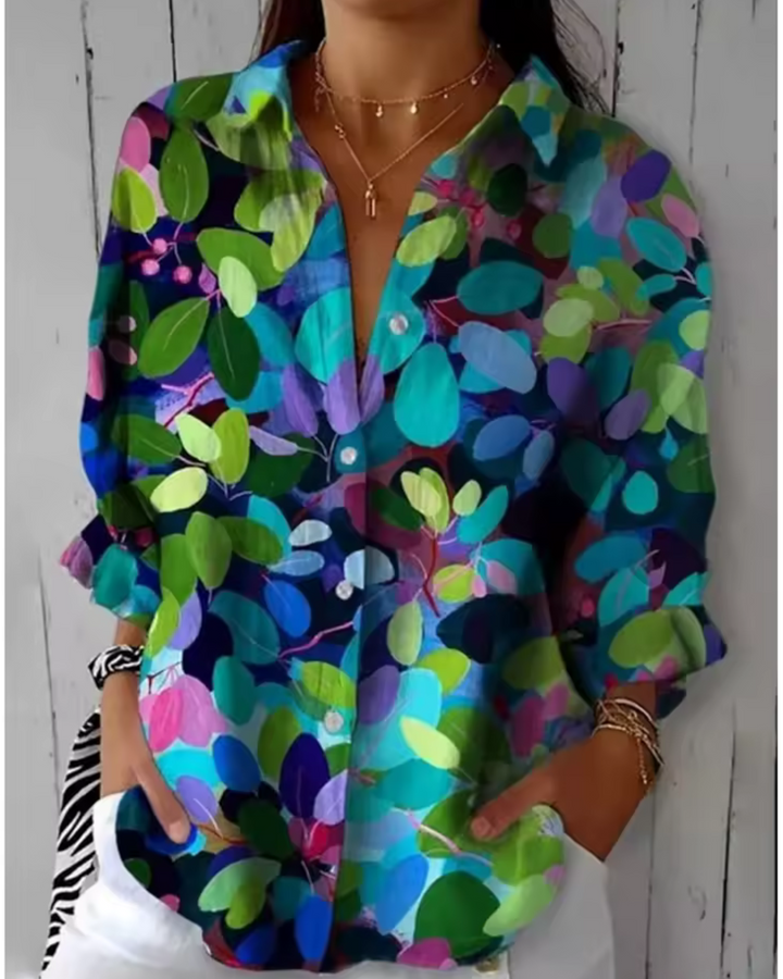 Elizabeth Chic Timeless Blouse, front view worn by model, with a vibrant abstract print and hands in pockets
