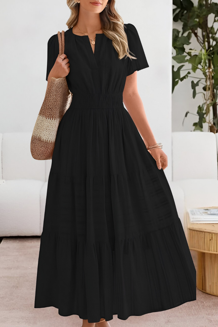 Front view of a woman wearing a black Boho Breeze summer dress with a smocked waist and tiered skirt