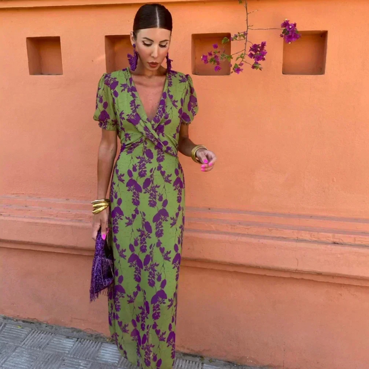Front view of a model wearing a green V neck maxi dress with purple floral print and gold bangles