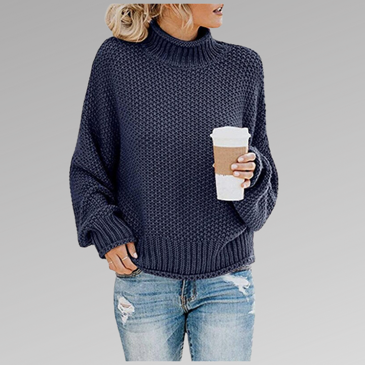 Front view of model wearing the navy Jovana Airy Touch Knit top with ripped jeans and holding a coffee cup