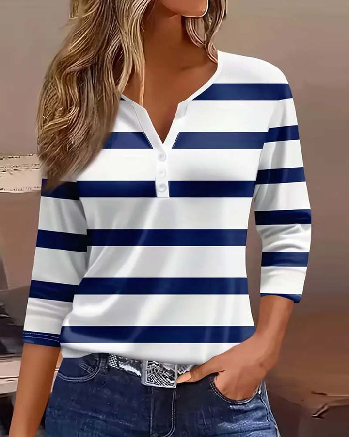 Front view of a model wearing a white and navy striped V-neck long sleeve shirt with three white buttons