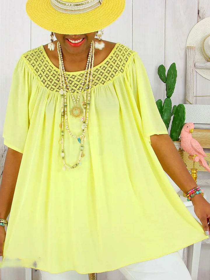 Close up, model wearing a bright yellow loose fit summer lace top with a wide brim hat and beaded necklaces