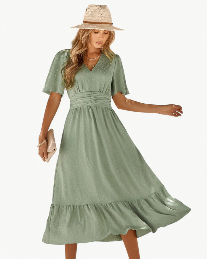 Front view, worn by model, a V-neck maxi dress with short sleeves in sage green, with a woven sun hat
