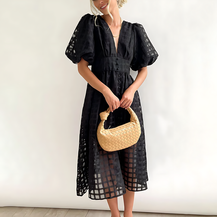 Front view of an elegant black summer midi dress with puff sleeves worn by a model holding a woven handbag