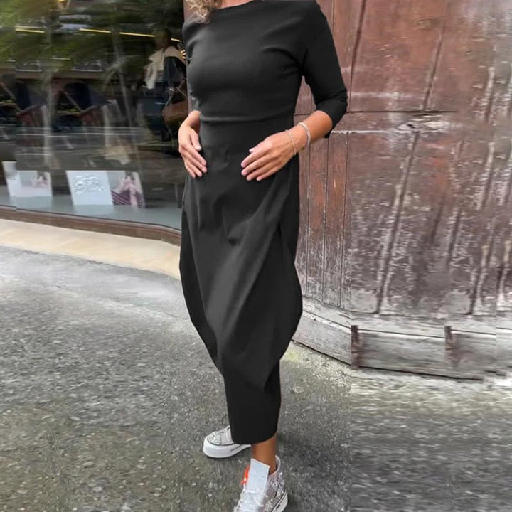 Front view of a model wearing the black Lana A-Line Dress with hands on her stomach and white sneakers