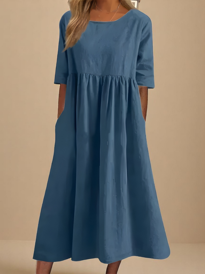 Back view of a model wearing a light blue soft cotton airy dress with gathering and side pockets
