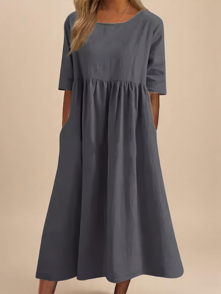 Front view of a model wearing a dark grey soft cotton airy dress with three quarter sleeves and side pockets