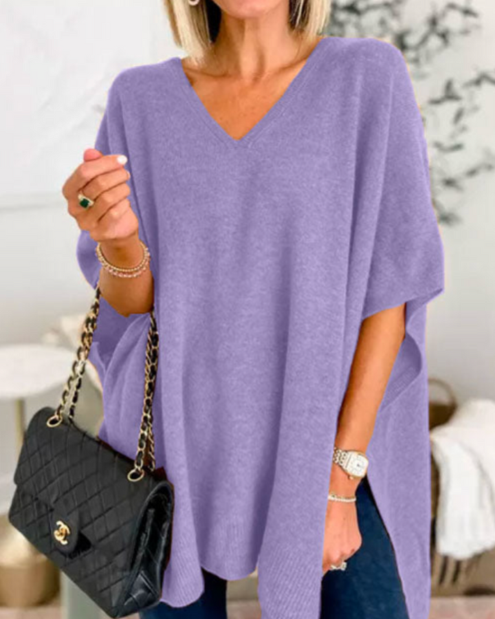 Front view of model wearing the Erica oversized V-neck poncho sweater in lavender, holding a black handbag