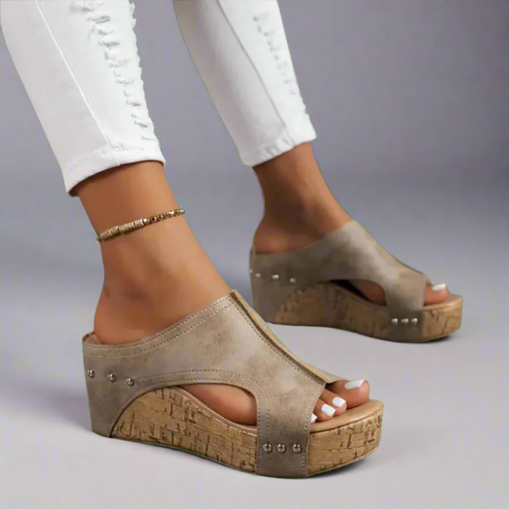 Three quarter view, elegant summer wedge sandals with taupe upper and studded cork-look soles, white jeans